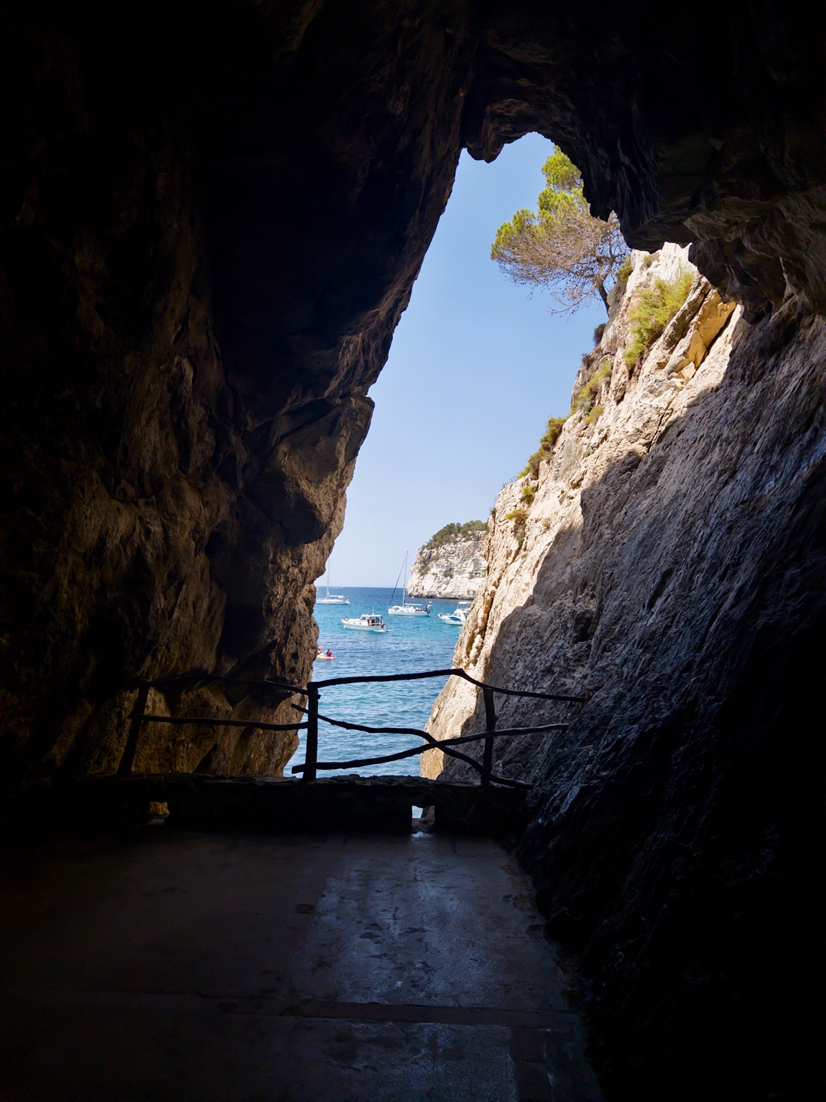 Arc de cova marina a Cala Galdana amb vistes a aigües turqueses i vaixells ancorats