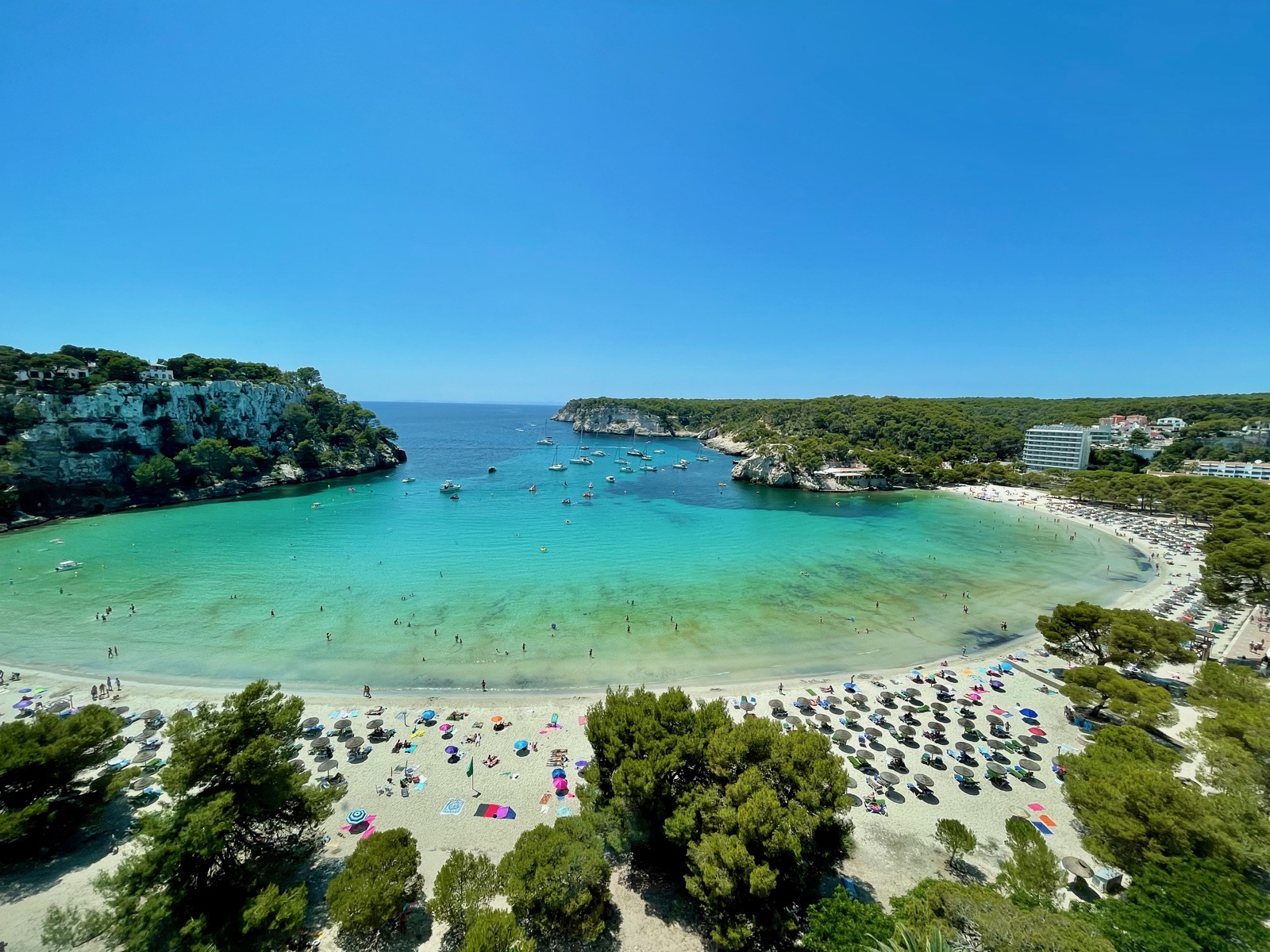 Vista aèria de la badia de Cala Galdana plena de banyistes i vaixells a l'estiu
