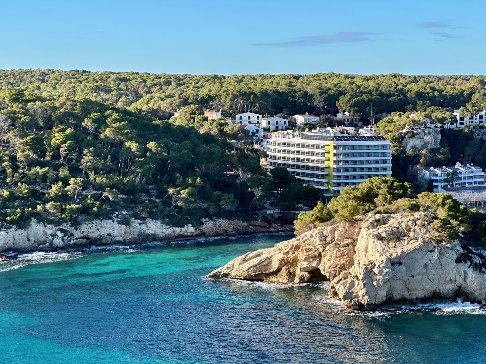 Hotel i villes encaramallats sobre penya-segats de calcària damunt les aigües turqueses de Cala Galdana