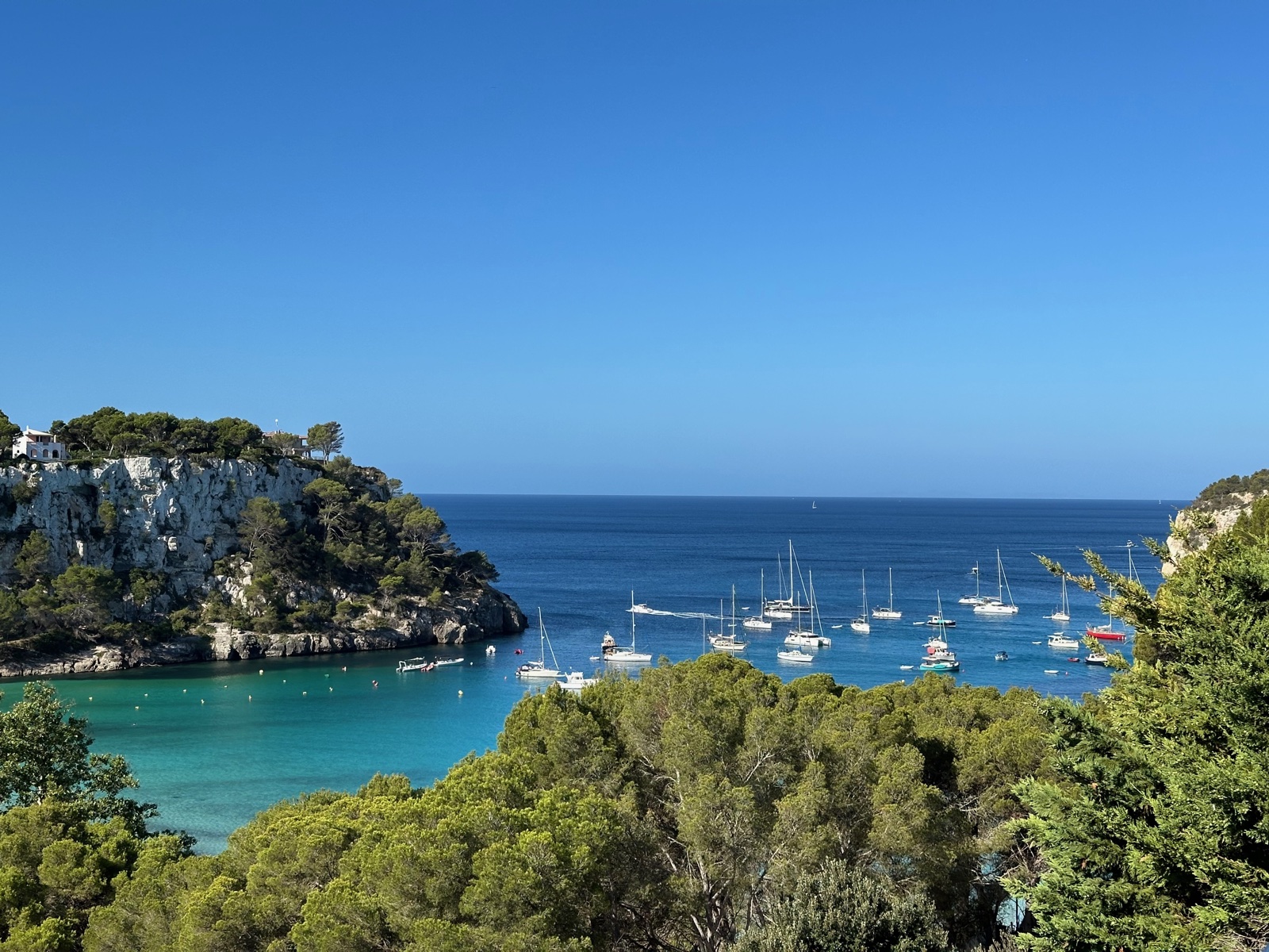 Badia de Cala Galdana amb velers ancorats en aigües turqueses, vista des de dalt